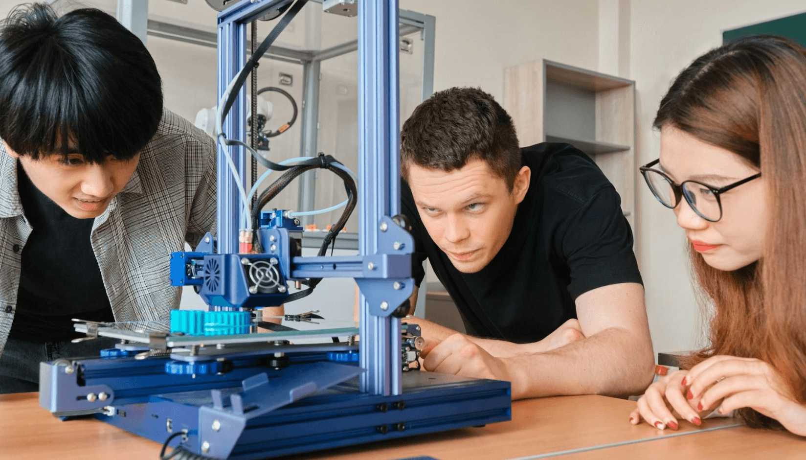 Makers working on 3D printer at a makerspace.